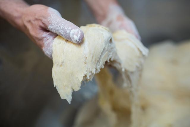 Close-up of hands kneading dough, perfect for illustrating baking, cooking, and homemade food preparation. Useful for culinary blogs, recipe websites, and cooking tutorials.