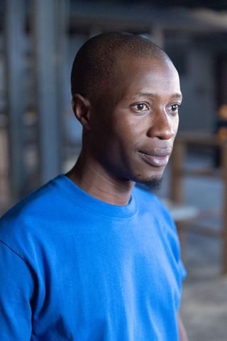 African american craftsman standing in industrial workshop wearing blue shirt, thoughtful portrait