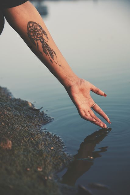 Dreamcatcher Tattooed Arm Touching Tranquil Lake Surface - Download Free Stock Photos Pikwizard.com