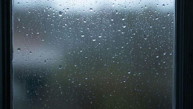 Rainy Window with Water Droplets Distorting Suburban View Through Glass Pane