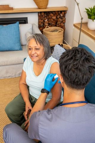Senior hispanic woman receiving home vaccination from nurse