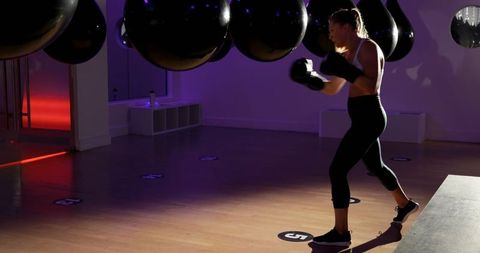 Female boxer training with punching bags in a well-lit studio