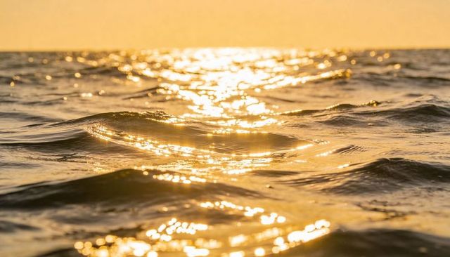 Golden sunlight shimmering on ocean waves at sunset with sparkling reflections
