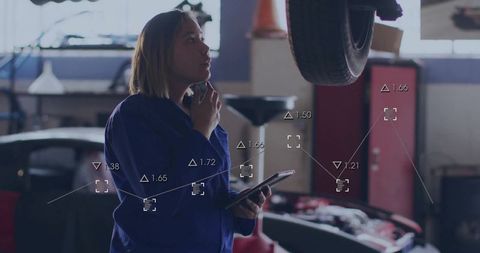 Female auto technician using technology in garage workshop