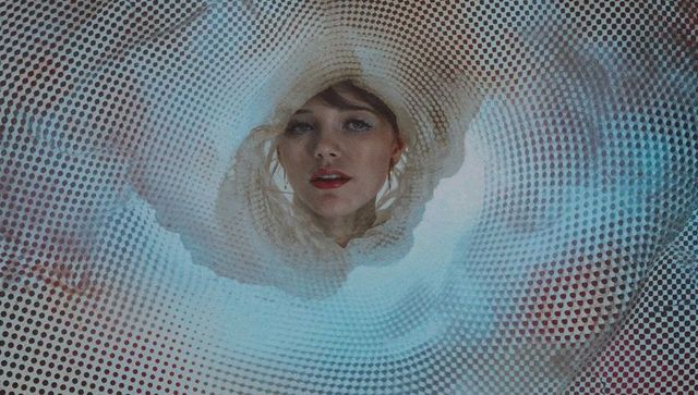 Woman peering through tubular mesh with abstract textured background