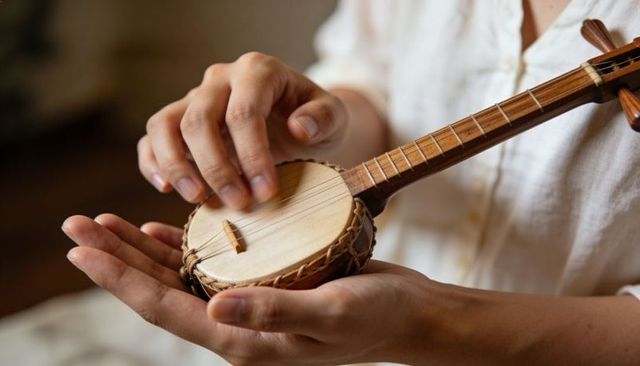 Closeup hands playing miniature round lute plucking strings on acoustic folk instrument