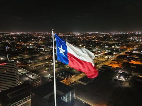 Texas Flag Over Urban Nightscape with City Lights