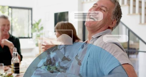 Mature friends laughing and chatting around dining table sharing meal and wine at home