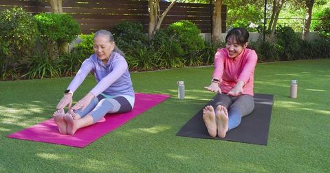 Senior and Adult Women Enjoying Yoga Outdoors in Lush Greenery