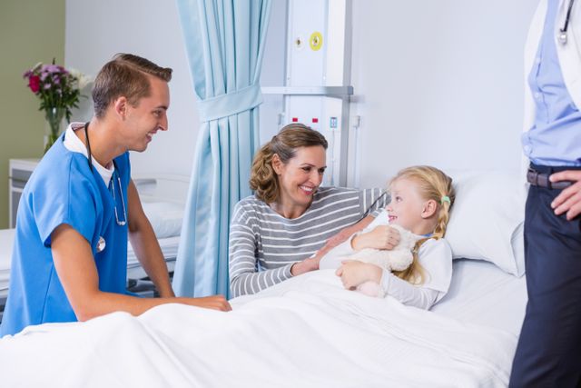 Smiling doctor talking with patient and mother in hospital room