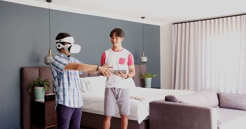 Father Using VR Headset with Son Observing at Home