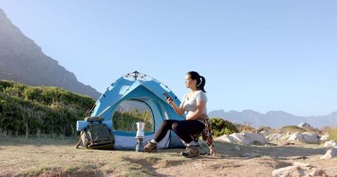 Woman Enjoying Mountain Campsite Using Smartphone