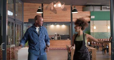 African american barista and customer greeting while entering cozy modern coffeehouse