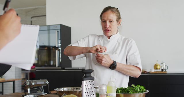 Female chef opening a container amidst food preparations in a professional kitchen setting. Visible are various ingredients and cooking tools, placing emphasis on food preparation and cooking techniques. Useful for articles about culinary arts, chef training programs, or cooking tutorials.