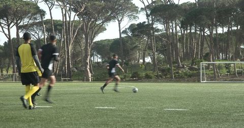 Soccer Players Practicing on Tree-Lined Field