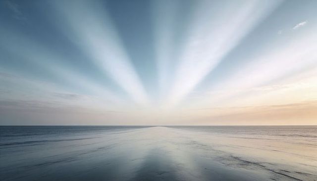 Sunbeams radiating over calm ocean horizon mirroring soft pastel sky