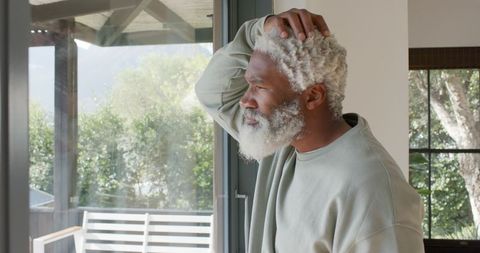 Contemplating man looking through glass door at home
