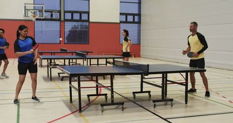 Diverse Group Enjoying Table Tennis in Indoor Gym Setting