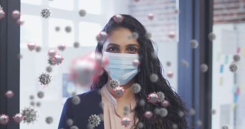 Mixed race woman in office with virus graphics overlay