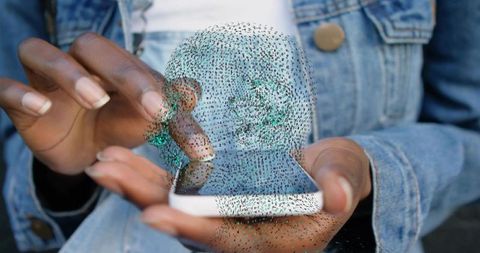 Hands tapping smartphone projecting digital skull hologram for cybersecurity concept