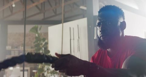 Focused Athletic Male Pulling Battle Rope in Modern Gym