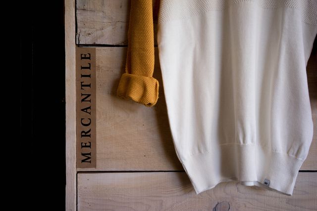 Sweater hanging on a rustic wooden wall with folded sleeves suggests a cozy, autumn aesthetic. Ideal for use in advertisements for clothing stores, fashion blogs, or autumn-themed promotional materials.