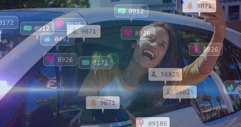Joyful woman taking car selfie with social media bubble graphics