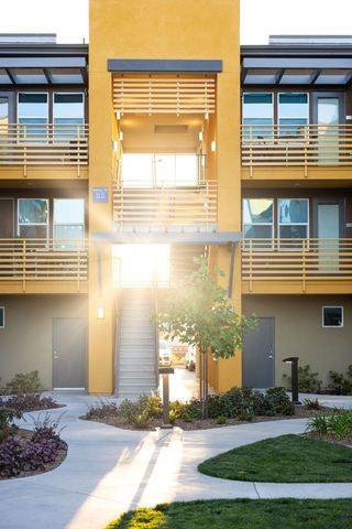 Modern Apartment Complex with Vibrant Yellow Facade and Sunlight