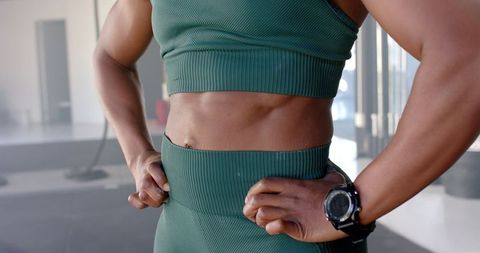 Athletic woman flaunting toned abs and arms in gym