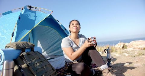 Woman Relaxing with Coffee at Mountain Campsite