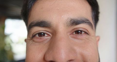 Close-up portrait of man examining skin near natural window light