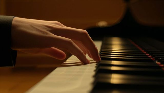 Intimate close-up pianist hand playing piano keys in warm low lighting