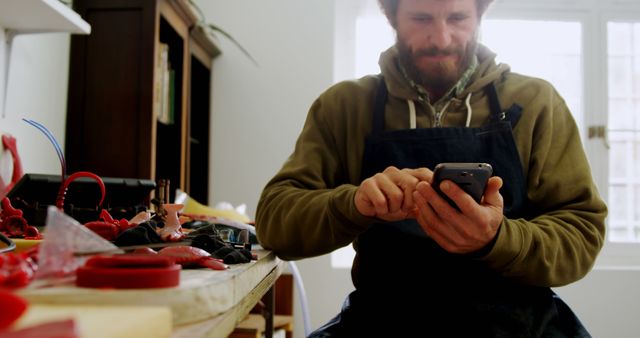 Craftsman Using Smartphone in Workshop with Tools on Workbench - Download Free Stock Images Pikwizard.com