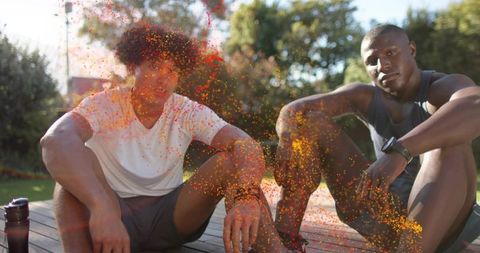 Young men resting on backyard deck after workout surrounded by vibrant orange powder