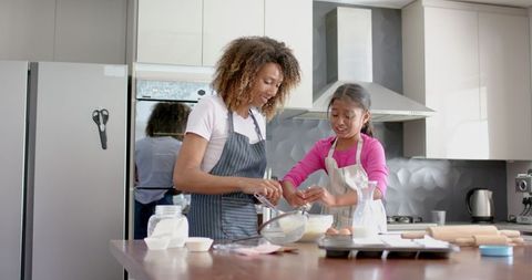 Biracial Mother and Daughter Enjoying Baking Together in Modern Kitchen