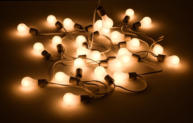Warm glowing light bulbs in a tangled arrangement emitting soft illumination perfect for creating a cozy atmosphere or festive feel. Ideal for use in articles related to home decor, lighting solutions, energy-efficient light sources, or as a background for promotional material in lighting and decoration industries.