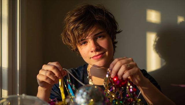 Teen smiling during golden hour handling colorful tinsel and disco ball, intimate portrait