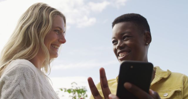 Two Friends Laughing and Using Smartphone Outdoors - Download Free Stock Images Pikwizard.com