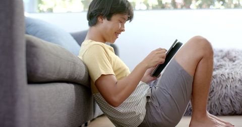 Asian Student Studying on Tablet by Sofa