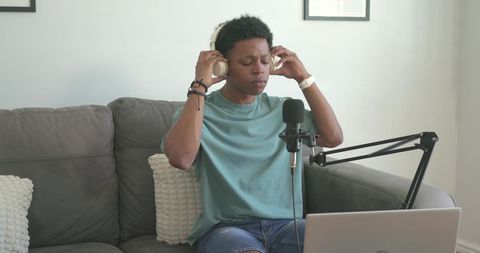 African american podcaster adjusting headphones and microphone in casual home studio setup