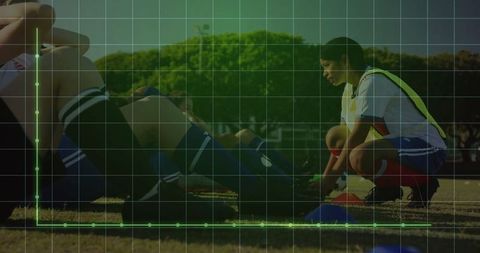Soccer athlete tying cleats on green field during training