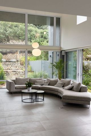Curved gray sectional sofa in minimalist living room with floor-to-ceiling windows