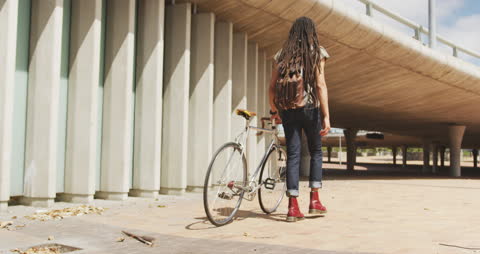 Man with Dreadlocks Walking Bicycle in Urban Environment