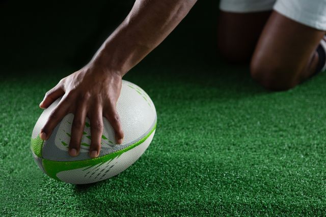 This image captures a close-up view of a rugby player holding a ball on a green field. Ideal for use in sports-related content, articles about rugby, athletic training materials, or promotional materials for sports events and competitions.