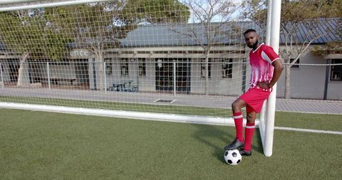 Confident Soccer Player Leaning on Goalpost