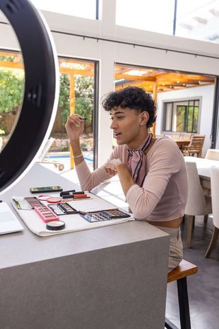 Male makeup artist demonstrating beauty techniques under ring light