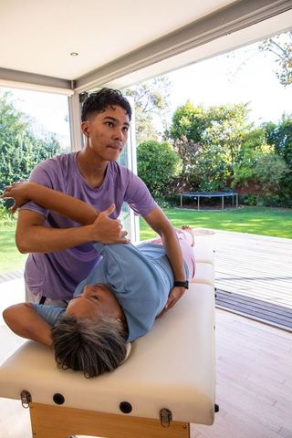 Therapist Adjusting Senior Patient in Home Studio for Rehabilitation