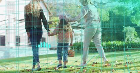 Walking multigenerational family holding hands on sunlit lawn with child carrying bucket