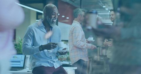 Smiling african american professional sipping coffee on office desk during coworker break