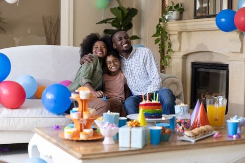 African american family home birthday party with rainbow layer cake and colorful balloons